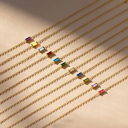 Collection of dainty stainless steel gold chain bracelets with colorful crystal birthstone charms displayed flat.