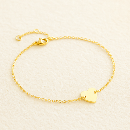 Adjustable gold stainless steel heart bracelet with dainty chain design on neutral background.
