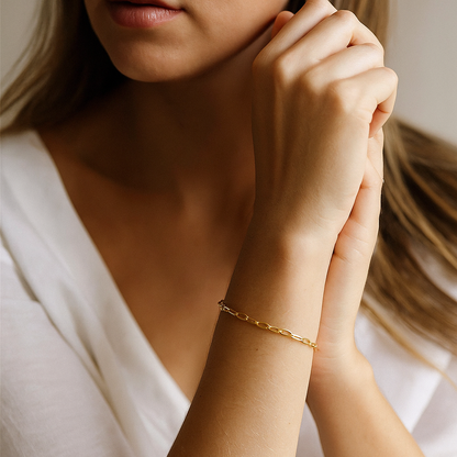 Elegant woman wearing minimalist gold stainless steel chain bracelet with elongated oval links.