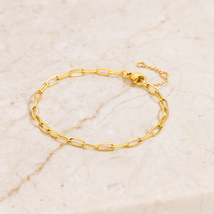 Gold minimalist chain bracelet with elongated oval links made of durable stainless steel on marble background.