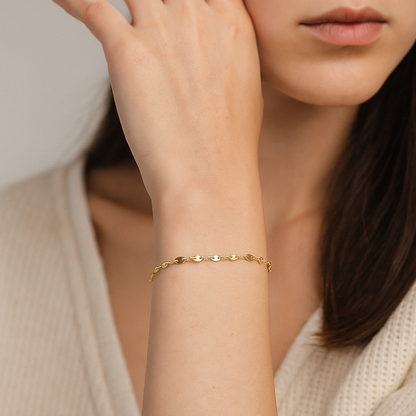 Minimalist gold stainless steel adjustable chain bracelet with flat oval links, styled on a woman’s wrist.