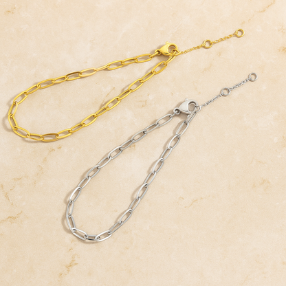 Pair of minimalist chain bracelets in gold and silver stainless steel with oval links side by side.