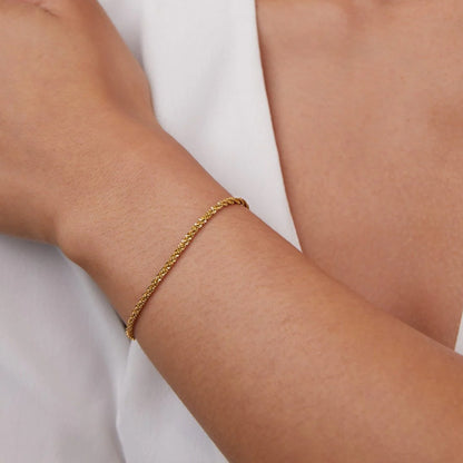 Elegant woman wearing gold sparkling gypsophila bracelet with minimalist chain design.
