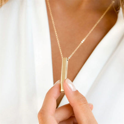 Close-up of gold stainless steel bar pendant necklace styled with a white blouse for a modern look.