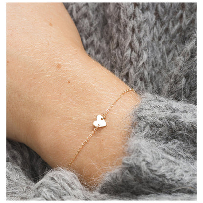 Dainty heart pendant bracelet in silver stainless steel, styled on wrist with cozy sweater.