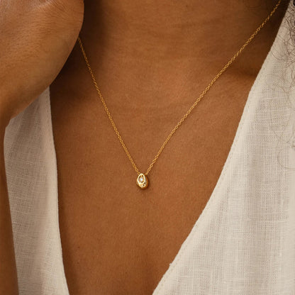 Woman wearing a dainty gold stainless steel water drop pendant necklace layered with another chain.
