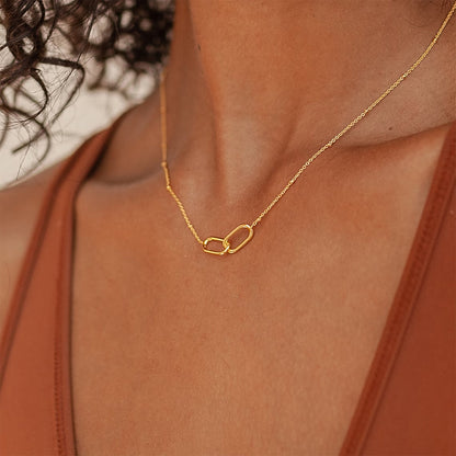 Model wearing a chic gold infinity link pendant necklace on a fine stainless steel chain with a rust-toned top.