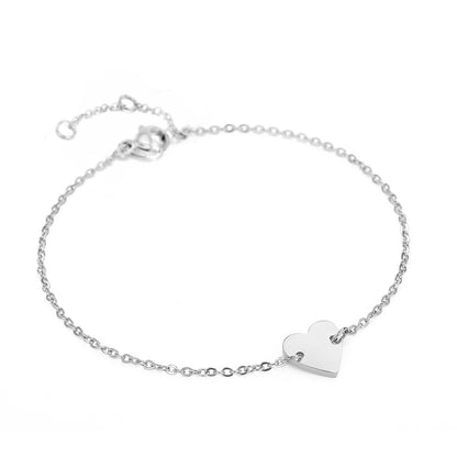 Minimalist silver stainless steel bracelet with polished heart pendant charm, elegant jewelry design.